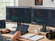 High-tech workspace focused on 截图软件下载 with developer coding, dual monitors, and natural light ambiance.